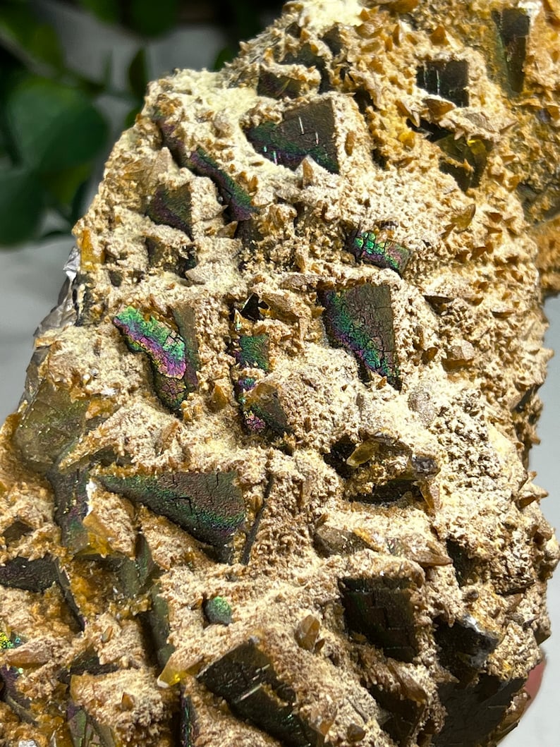 May include: A close-up of a brown and gold iridescent mineral specimen with a rough, textured surface. The mineral has a variety of crystal shapes and sizes, and it is covered in a layer of fine, sparkling crystals.