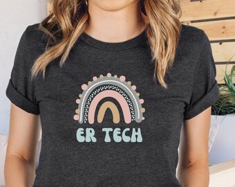 May include: Dark gray t-shirt featuring a colorful rainbow design with the text "ER TECH" in a playful font. The rainbow includes shades of pink, beige, and blue. The shirt has rolled-up sleeves.