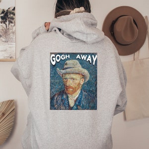 Puede incluir: Una sudadera gris con una pintura de Vincent van Gogh en la espalda. La pintura es un autorretrato de van Gogh y el texto "GOGH AWAY" está impreso sobre la pintura.