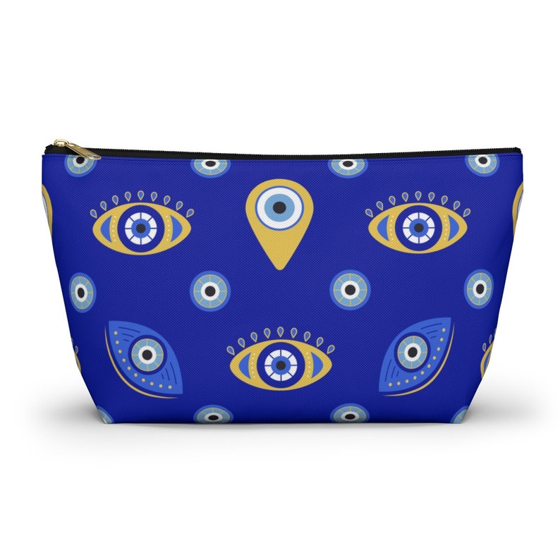 Peut inclure: Une pochette zipp&eacute;e bleue avec un motif r&eacute;p&eacute;t&eacute; d'yeux mal&eacute;fiques bleus et jaunes. La pochette est faite d'un tissu doux et durable et est parfaite pour ranger de petits objets.