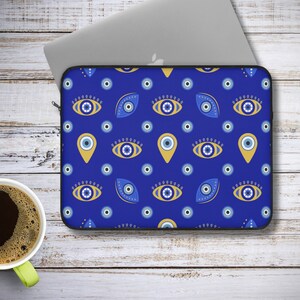May include: Blue laptop sleeve with a pattern of yellow and blue evil eyes. The evil eyes are in different shapes and sizes, including circles, ovals, and teardrops.