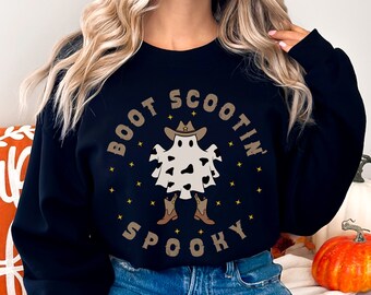 May include: Black sweatshirt featuring a white ghost wearing a cowboy hat and boots. The text "Boot Scootin Spooky" is printed in a circle around the ghost.