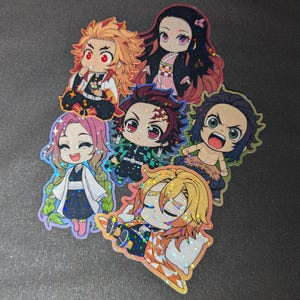 May include: A collection of seven holographic stickers featuring anime characters with large eyes and vibrant colors. The characters have various hair colors, including red, pink, and blonde, and are dressed in detailed outfits. The stickers are likely for fans of anime.