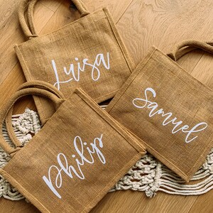Pode incluir: Tr&ecirc;s sacos de juta marrons com letras brancas. Os sacos t&ecirc;m os nomes "Luisa", "Samuel" e "Philip" escritos neles.
