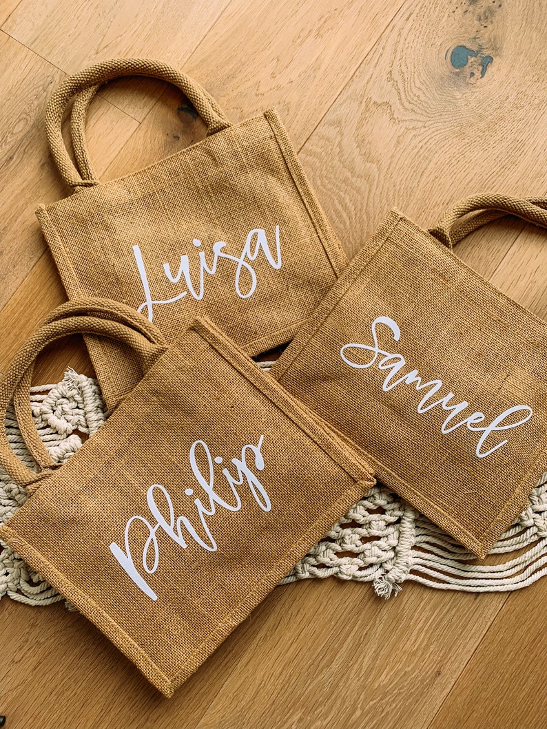 Pode incluir: Tr&ecirc;s sacos de juta marrons com letras brancas. Os sacos t&ecirc;m os nomes "Luisa", "Samuel" e "Philip" escritos neles.
