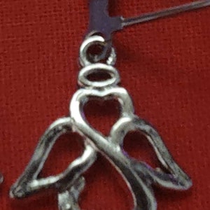 May include: Silver angel wing earrings with a heart design. The earrings are made of a delicate, intricate metalwork.