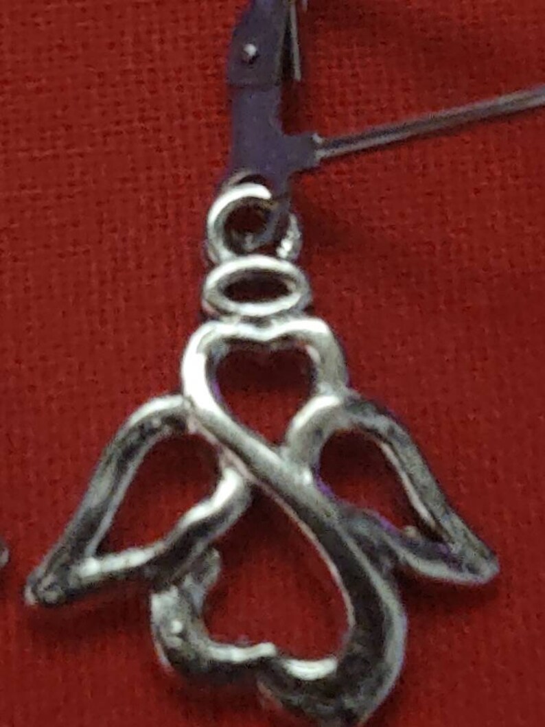 May include: Silver angel wing earrings with a heart design. The earrings are made of a delicate, intricate metalwork.