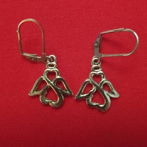 May include: A pair of gold-toned angel wing earrings with a heart design. The earrings have a simple hook closure.