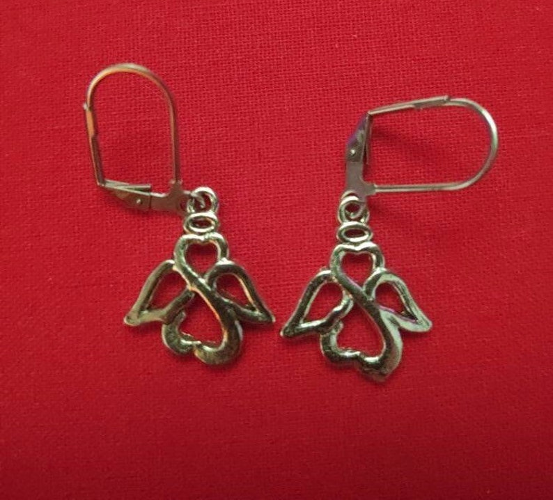 May include: A pair of gold-toned angel wing earrings with a heart design. The earrings have a simple hook closure.