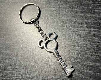 May include: Silver key chain with a Mickey Mouse shaped key charm. The key has a twisted design and a small loop at the top.