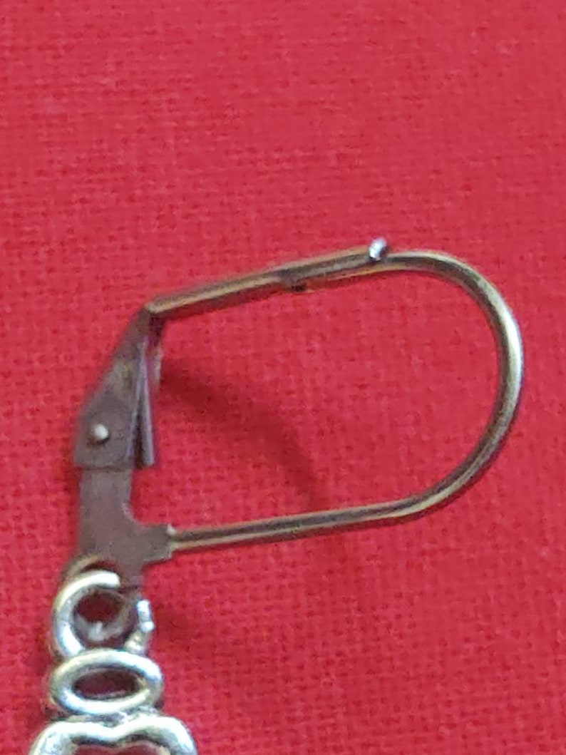 May include: Silver earring with a hook closure. The hook is made of metal and has a smooth finish.