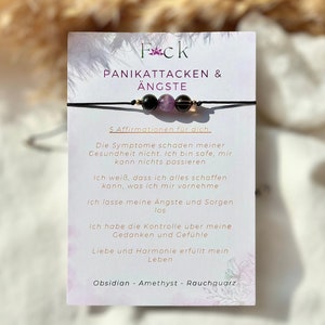 Könnte beinhalten: Ein schwarzes Armband aus Schnur mit drei Perlen: Obsidian, Amethyst und Rauchquarz. Das Armband wird von einer Karte mit dem Text "Fck Panikattacken & Ängste" und fünf Affirmationen zur Bewältigung von Panikattacken und Angst begleitet.