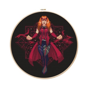 May include: A cross-stitch pattern featuring a red-haired woman in a red and black costume with a geometric design behind her.