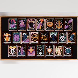 Può includere: Un ricamo a punto croce incorniciato che presenta ventidue carte dei tarocchi disposte su tre file. Ogni carta mostra immagini pixelate ed etichette di testo come The Fool, The Magician, The Empress, The Emperor, The Lovers e The World in colori vivaci.
