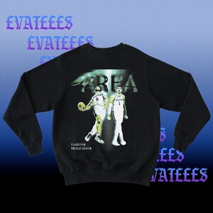 K&ouml;nnte beinhalten: Schwarzes Sweatshirt mit einer Grafik von zwei Basketballspielern und dem Wort "AREA". Der Text "EVATEEES" wird in Lila wiederholt. Das Sweatshirt tr&auml;gt auch den Text "CLASSIFICATION: PROJECT SEATEN".