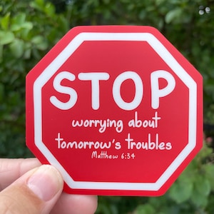 May include: A red, octagonal sticker with white border and text. The word "STOP" is at the top, with "worrying about tomorrow's troubles" below. The text "Matthew 6:34" is at the bottom.