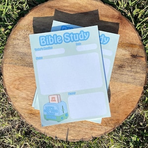 May include: Light blue Bible study notepads with the words "Bible Study" at the top. The notepad has sections for "Today's Reading", "Notes", "Date", and "Prayer". A cartoon toaster with the words "Let's Get This Daily Bread" is at the bottom.