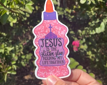 May include: A pink glitter glue sticker with the text "JESUS is the glitter glue holding my life together." The sticker is shaped like a glue bottle with a purple cap and orange tip. A cross is above the word "JESUS".