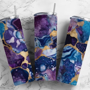 Peut inclure: Trois gobelets en acier inoxydable avec couvercles et pailles. Les gobelets sont décorés d'un motif abstrait marbré violet, bleu et or.