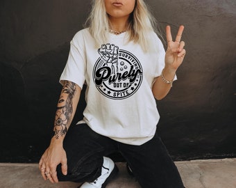 May include: Black and white graphic design on a white t-shirt. The design features a fist with the words "Surviving Purely Out of Spite" in a circle.