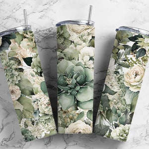 May include: Three stainless steel tumblers with a floral design featuring white flowers, green leaves, and succulents. The tumblers have a white background and are ideal for everyday use.