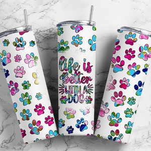 以下が含まれることがあります： 犬の足跡のデザインと「犬と一緒なら人生はもっと素晴らしい」というテキストが書かれた、白いステンレス製のタンブラーが3つあります。