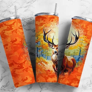 Puede incluir: Tres vasos de acero inoxidable con un patrón de camuflaje. Los vasos presentan una ilustración colorida de un ciervo en un entorno de bosque.