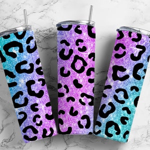 Pode incluir: Três copos de aço inoxidável com um design de glitter degradê em tons de azul e roxo. Os copos apresentam um padrão de leopardo preto.