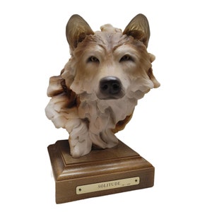 May include: A detailed ceramic sculpture of a wolf's head, with a realistic fur texture and a wooden base. The base has a brass plaque with the word "SOLITUDE" engraved on it.