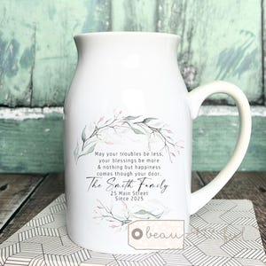 Pode incluir: Jarro de leite de cerâmica branca com um design floral e o texto "May your troubles be less, your blessings be more & nothing but happiness comes though your door. The Smith Family 25 Main Street Since 2025"
