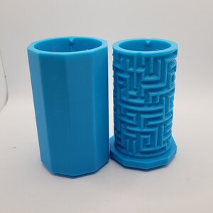 Op de afbeelding: Twee blauwe plastic mallen, een met een zeshoekige vorm en de andere met een labyrintpatroon.