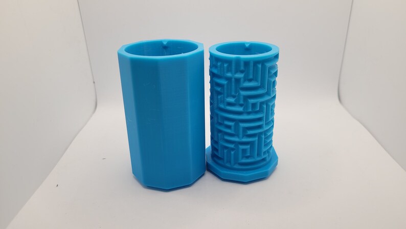 Op de afbeelding: Twee blauwe plastic mallen, een met een zeshoekige vorm en de andere met een labyrintpatroon.
