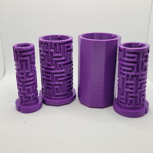 Op de afbeelding: Vier paarse 3D-geprinte cilindrische containers met een labyrintpatroon aan de zijkanten. De containers zijn van verschillende groottes en zijn in een rij gerangschikt.