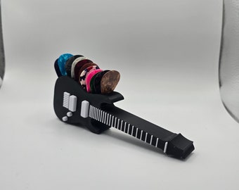 May include: A black guitar-shaped pick holder with a white pickguard and white fret markers. The holder is filled with a variety of colorful guitar picks.