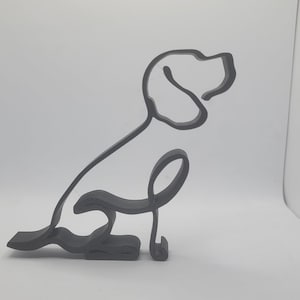 May include: A dark grey, minimalist dog sculpture in a sitting position. The artwork is a continuous line, creating a 3D effect. The dog's features, including the ear and tail, are clearly defined.