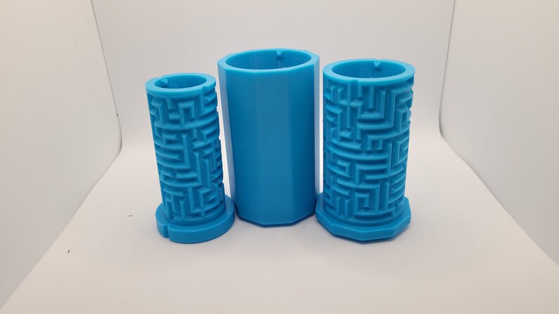Op de afbeelding: Drie blauwe plastic mallen voor het maken van betonnen plantenbakken. De mallen zijn cilindrisch en hebben een textuurpatroon van een doolhof aan de buitenkant.