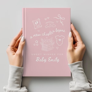 May include: A pink baby journal with white illustrations and text. The cover reads "a new chapter begins" and "Sweet Wishes for Baby Emily." The design includes a baby footprint, a onesie, and other baby-themed drawings.