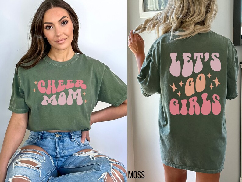 May include: Two green t-shirts with a retro font design. One shirt says "Cheer Mom" and the other says "Let's Go Girls".