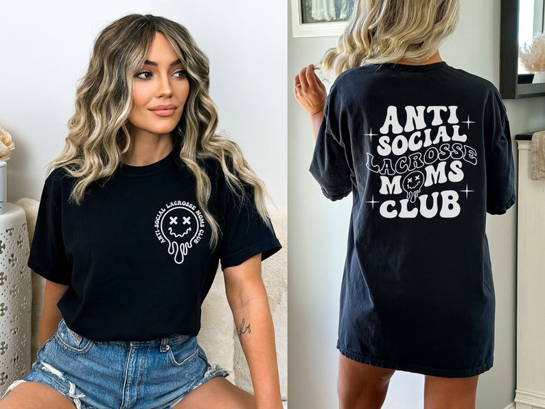 May include: Black t-shirt with a white graphic that says "Anti-Social Lacrosse Moms Club" and a dripping smiley face with X's for eyes.