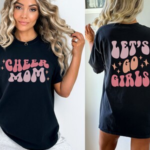 May include: Black t-shirt with a pink and orange "Cheer Mom" graphic on the front and a pink and orange "Let's Go Girls" graphic on the back.