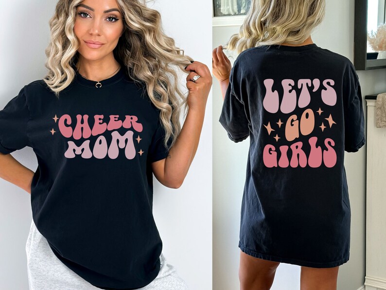 May include: Black t-shirt with a pink and orange "Cheer Mom" graphic on the front and a pink and orange "Let's Go Girls" graphic on the back.