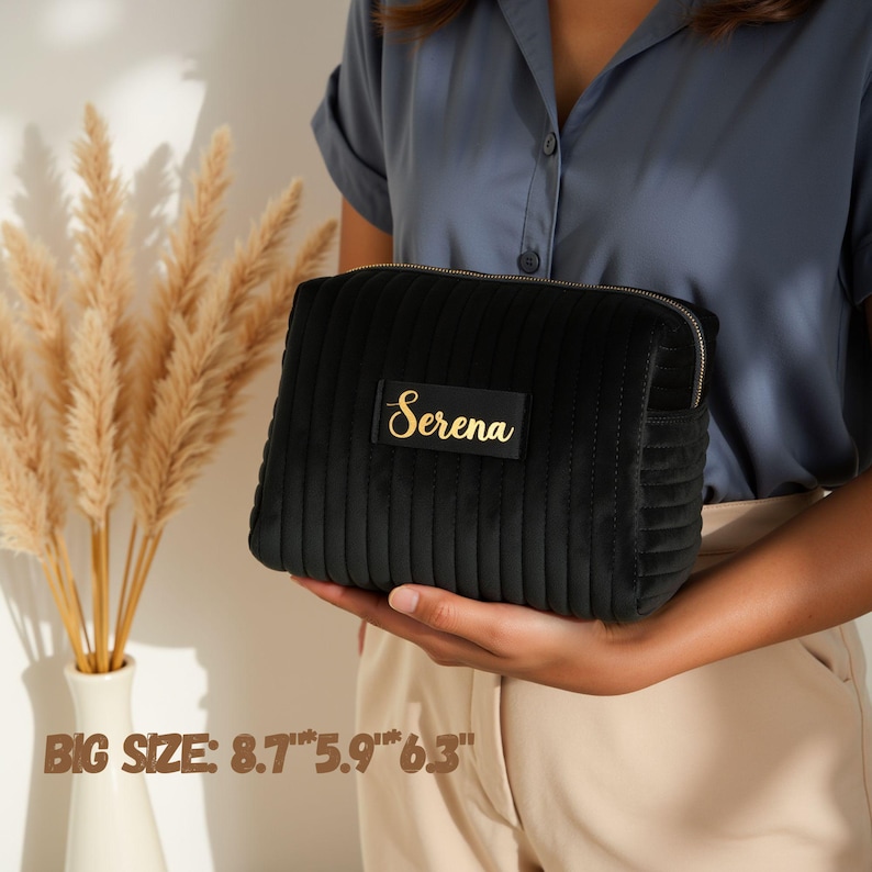 a woman holding a black purse with a name on it