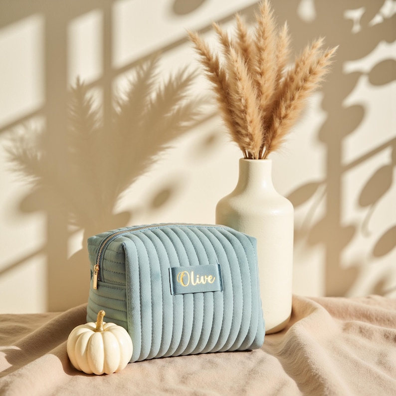 a blue purse sitting on top of a bed next to a vase