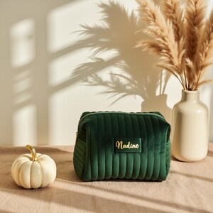 a green velvet bag sitting next to a white pumpkin
