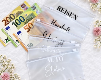 May include: A set of five clear, rectangular plastic zipper pouches with white plastic zippers and punched holes along the bottom edge. Each pouch features black or white printed text including the words REISEN, Haushalt, and Studium.