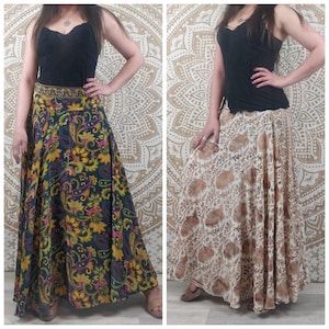 May include: Two women wearing long, flowing skirts with different floral patterns. The skirt on the left is black with yellow, pink, and green flowers. The skirt on the right is white with brown flowers. Both skirts are made of a soft, flowing fabric.