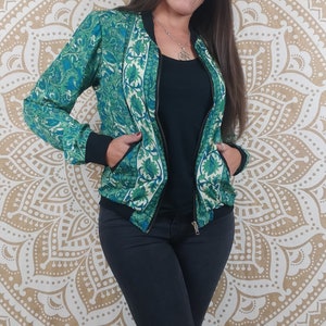 Può includere: Una giacca bomber con motivo verde e bianco con chiusura a zip. La giacca presenta un design floreale ed è realizzata in un tessuto morbido e setoso.