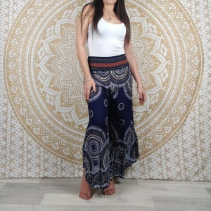 Puede incluir: Pantalones palazzo azul marino con un estampado circular blanco y gris. Los pantalones tienen una cintura ancha con un dise&ntilde;o rojo y naranja. La modelo lleva una camiseta sin mangas blanca. El fondo es un dise&ntilde;o de mandala dorado.