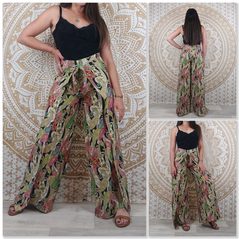 Op de afbeelding: Wijde broek met paisley print in tinten van groen, zwart, roze en goud. De broek heeft een strik in de taille en een split aan elke kant.