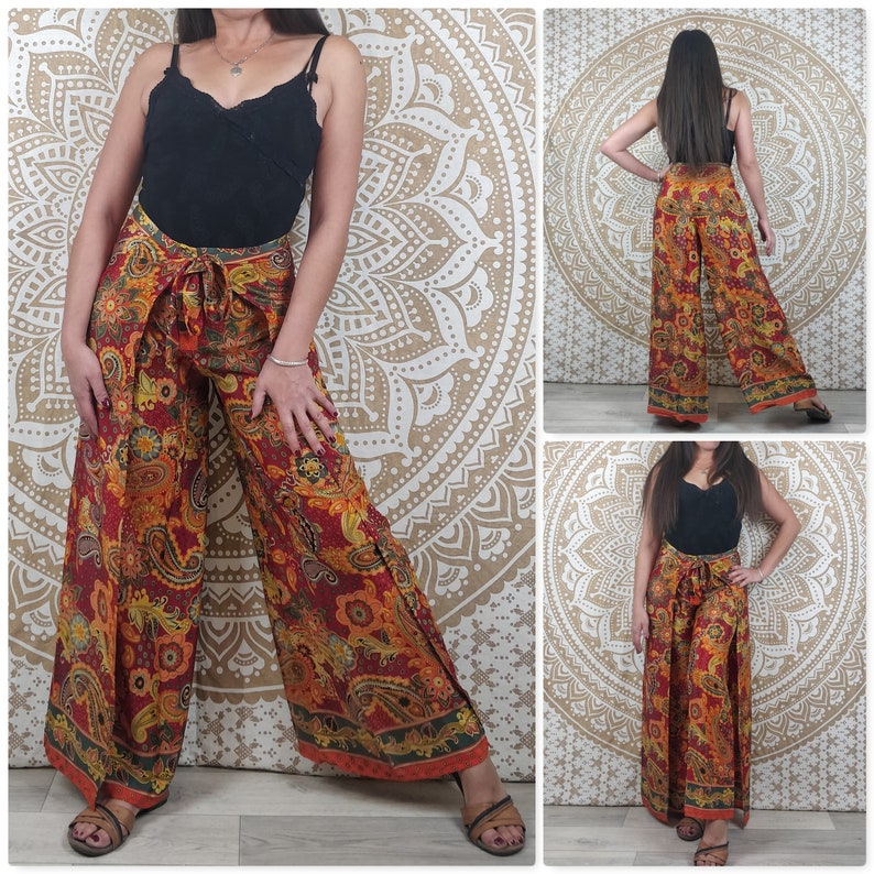 Op de afbeelding: Een wijde broek met paisley print in tinten rood, oranje en geel. De broek heeft een wikkel-stijl en een strik in de taille.